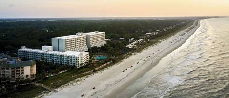 Un hotel costero con varias edificaciones, acceso directo a la playa y vista al océano.