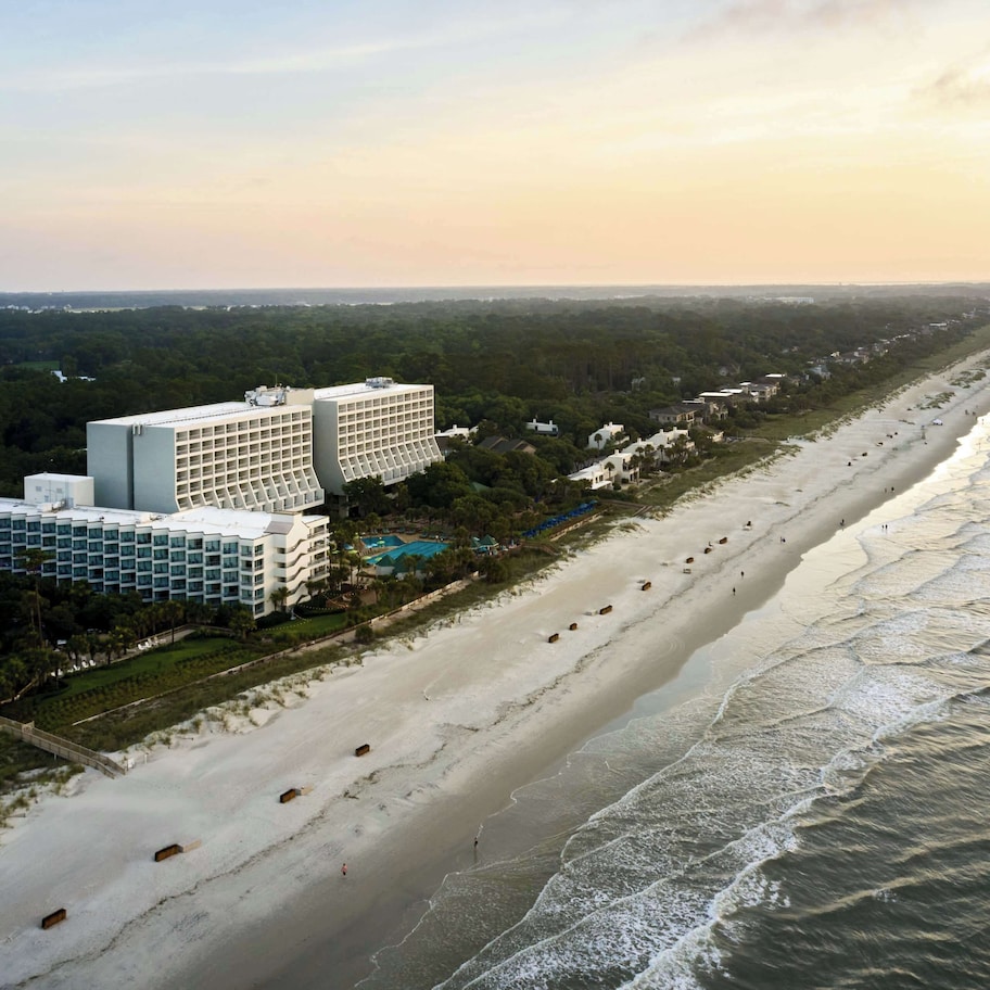 A coastal hotel with multiple buildings, a beachfront, and a view of the ocean.