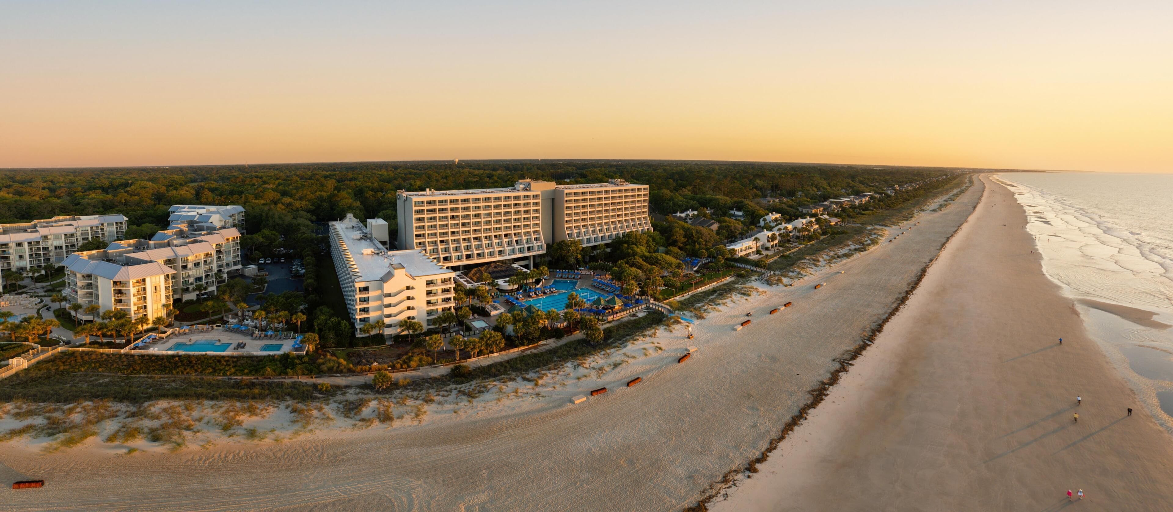 Un hôtel situé sur la côte, composé de plusieurs bâtiments, avec une plage et une piscine.
