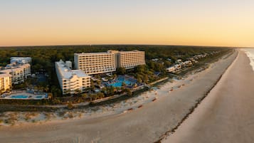 Un hôtel situé sur la côte, composé de plusieurs bâtiments, avec une plage et une piscine.