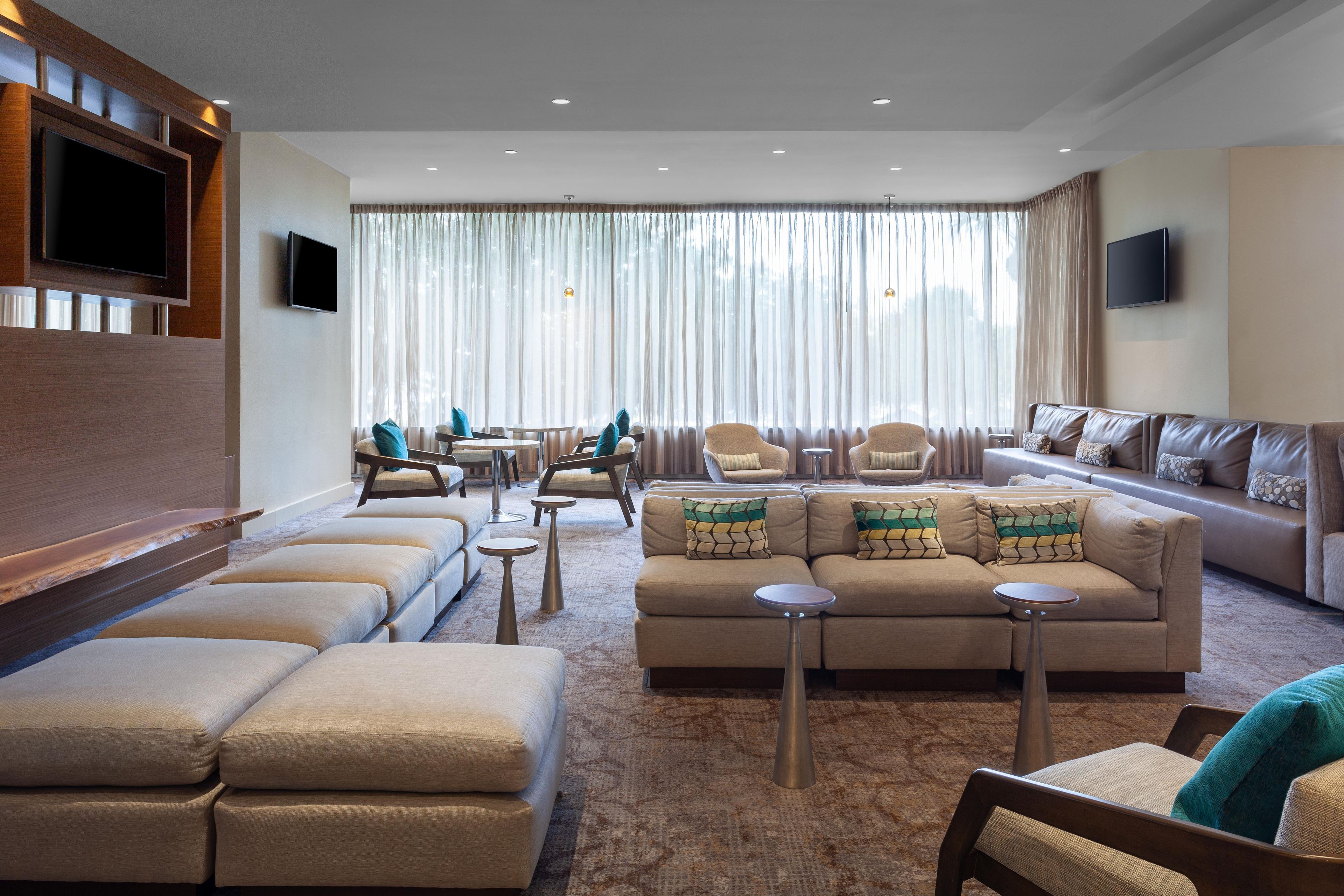 A modern living room with a sofa set, armchairs, and a flat-screen TV mounted on the wall.