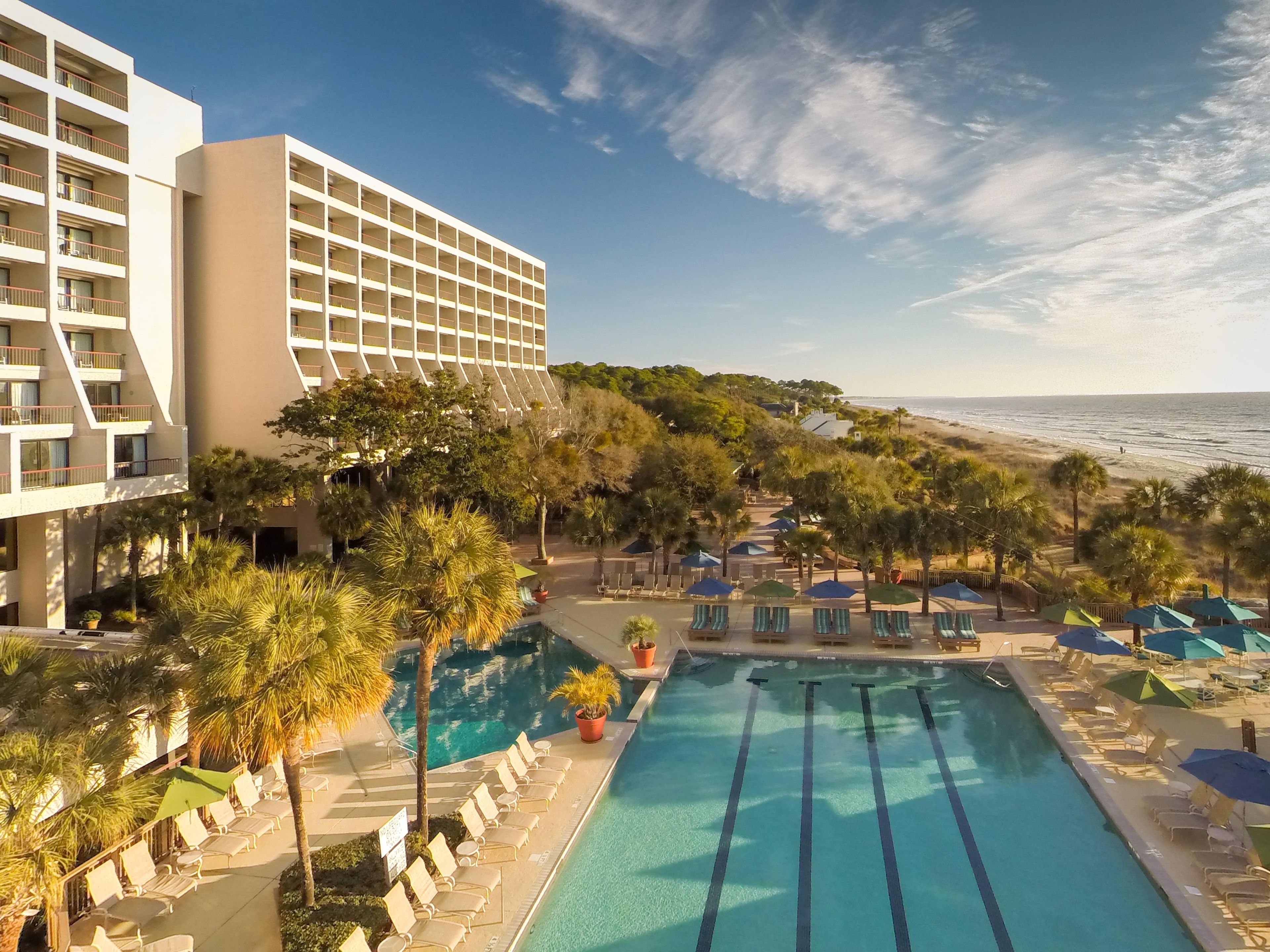 Ein Hotel mit Schwimmbad, Liegestühlen und Blick auf den Strand.