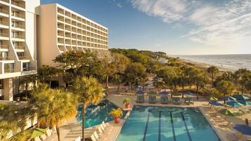 Un hôtel doté d’une piscine, de chaises longues et offrant une vue sur la plage.