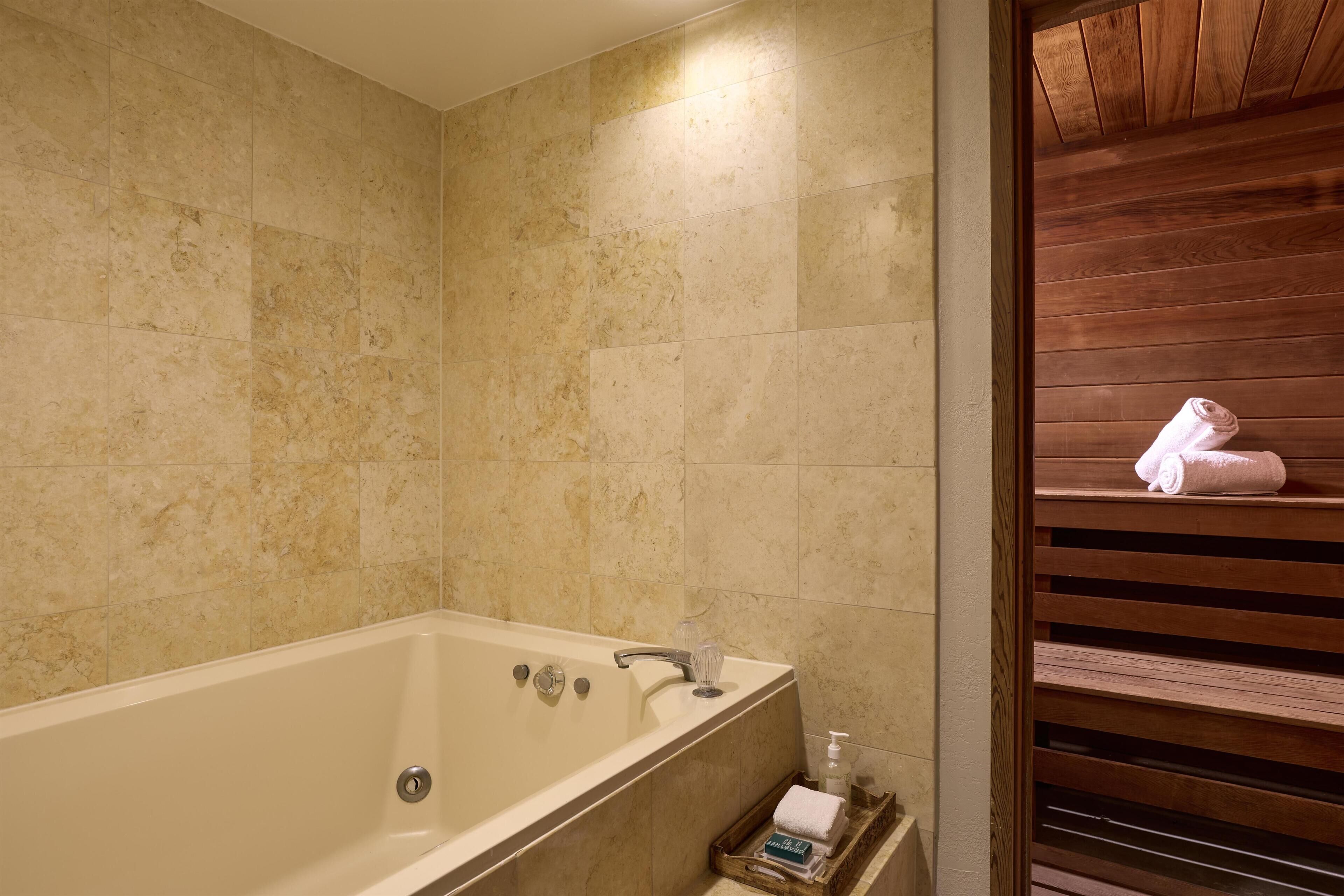 A bathroom with a bathtub, a wooden bench, and a towel rack.