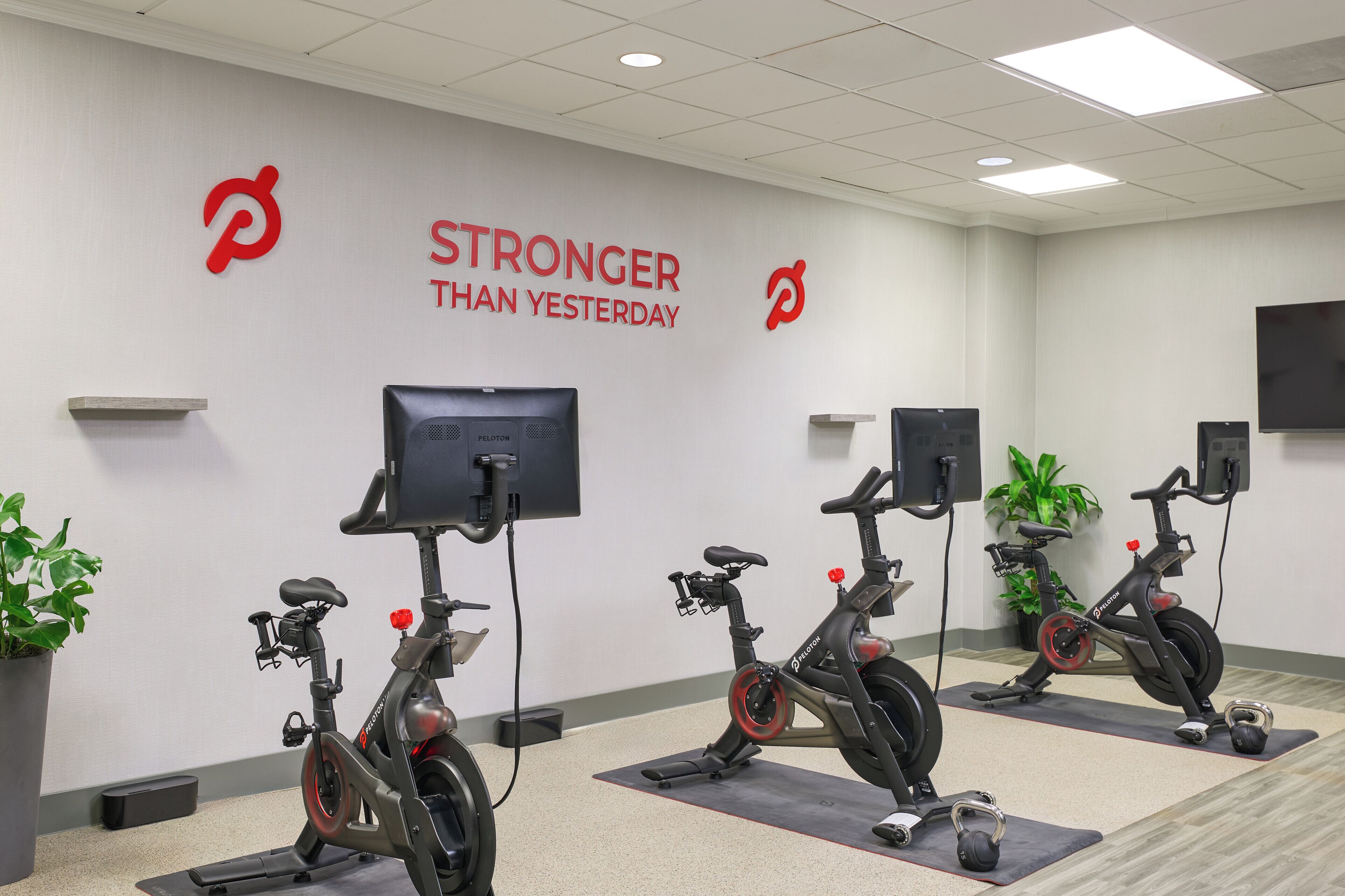Et fitnessrum med motionscykler, en motiverende plakat på væggen og et fjernsyn.