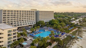 A hotel with multiple floors, a swimming pool, and a beach area.