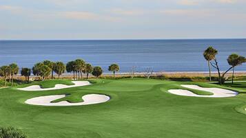 A golf course with sand bunkers and a view of the ocean.