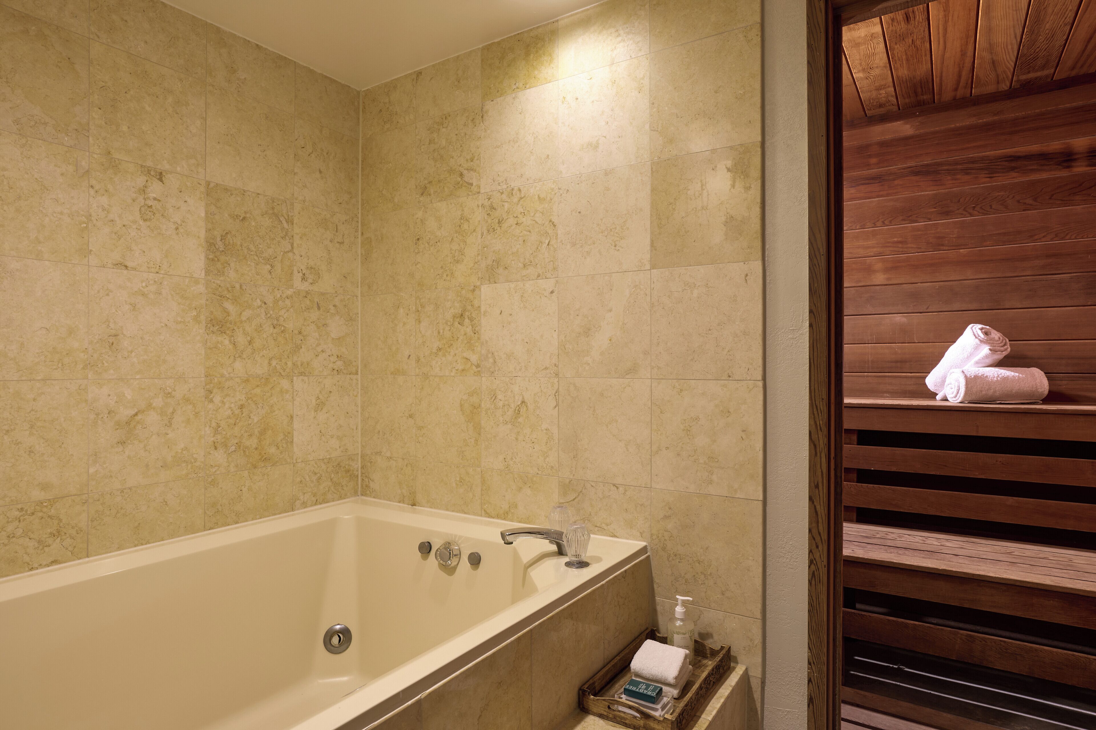 Ein Badezimmer mit einer Badewanne, einer Holzbank und einem Handtuchhalter.