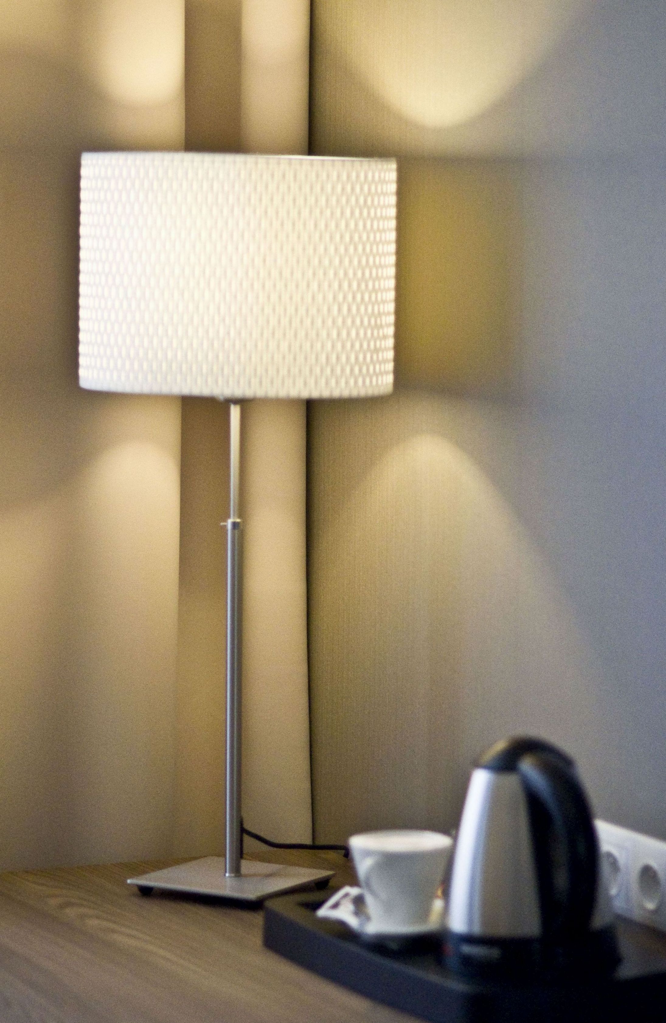 A modern lamp on a wooden table with a cup and a kettle.