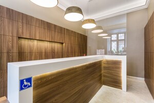 A reception desk with a wooden panel design, a wheelchair accessibility sign, and pendant lighting.