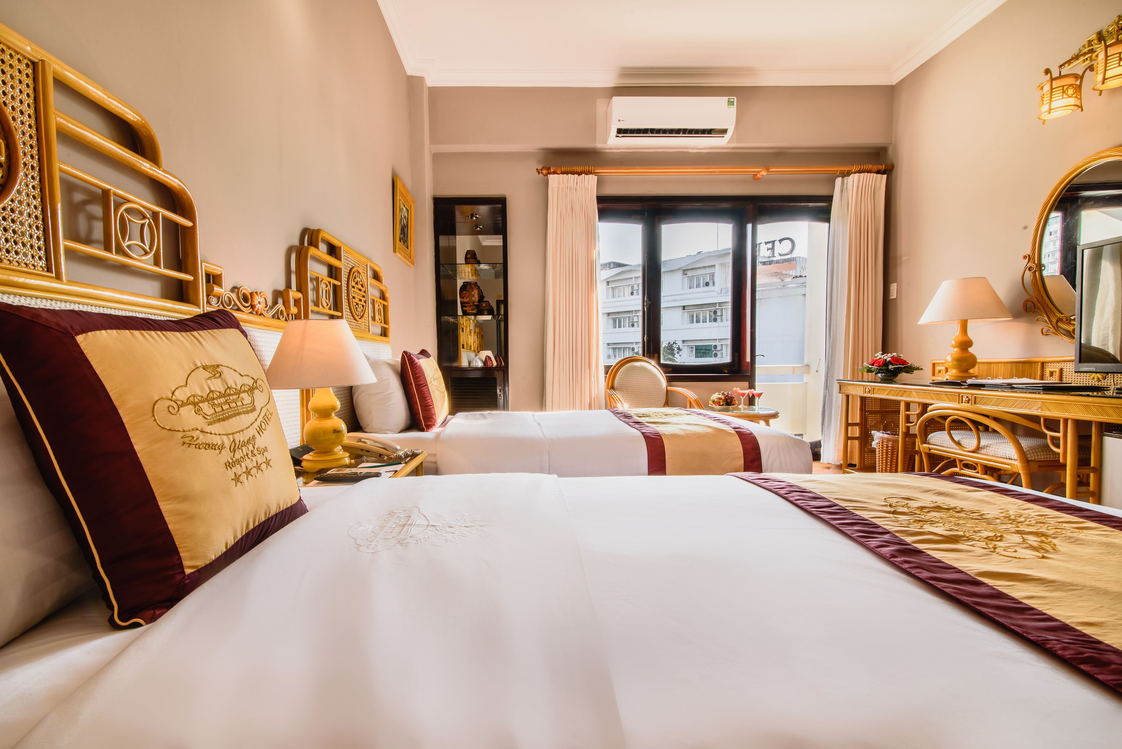 Habitación de hotel con dos camas, un escritorio, una silla y un ventanal grande.