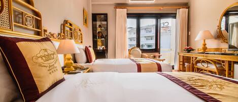 Habitación de hotel con dos camas, un escritorio, una silla y un ventanal grande.