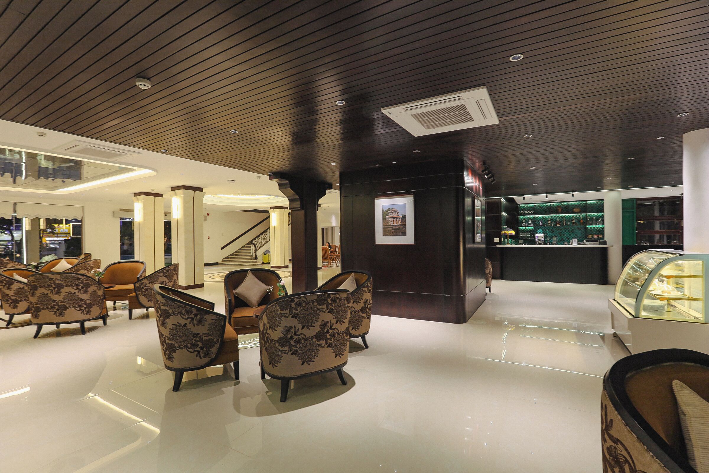 A lobby with modern furniture, a staircase, and a display case.