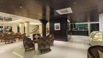 A lobby with modern furniture, a staircase, and a display case.