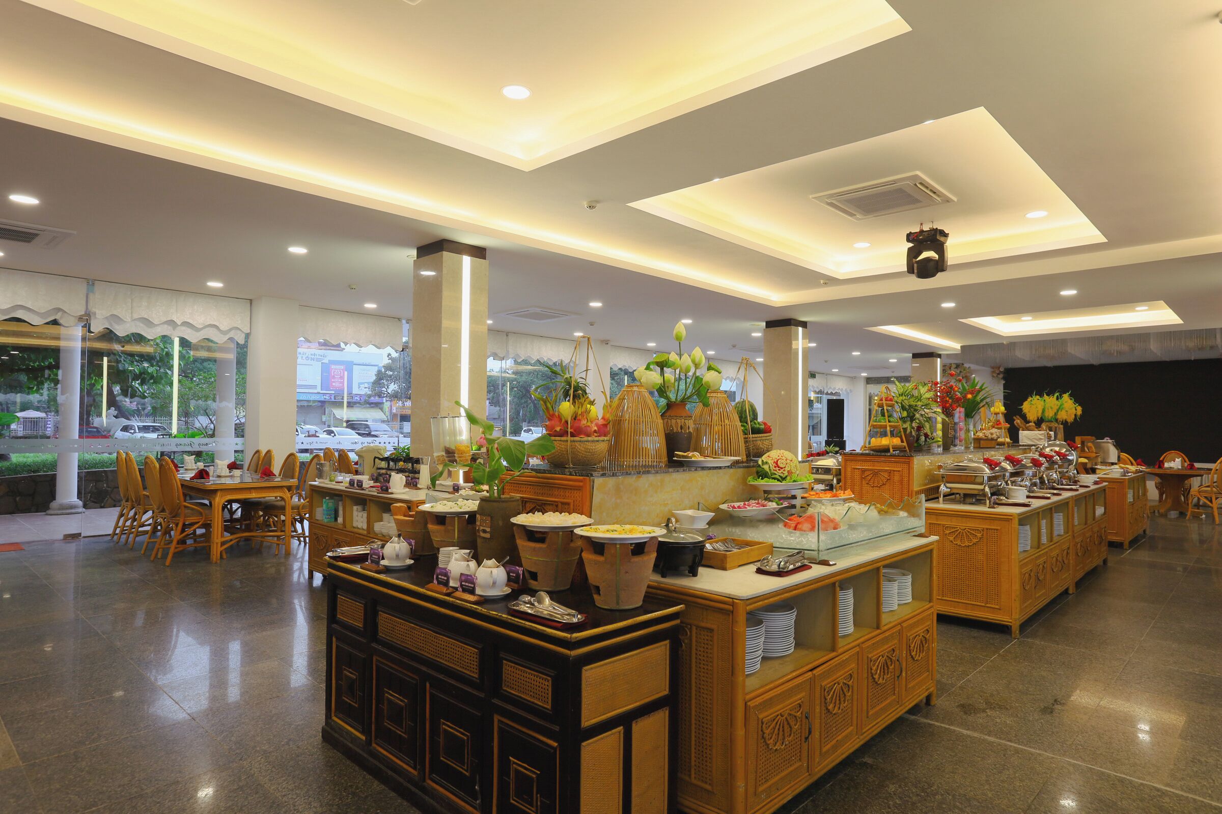 Vestíbulo de hotel con zona de bufé, arreglos de asientos y plantas decorativas.