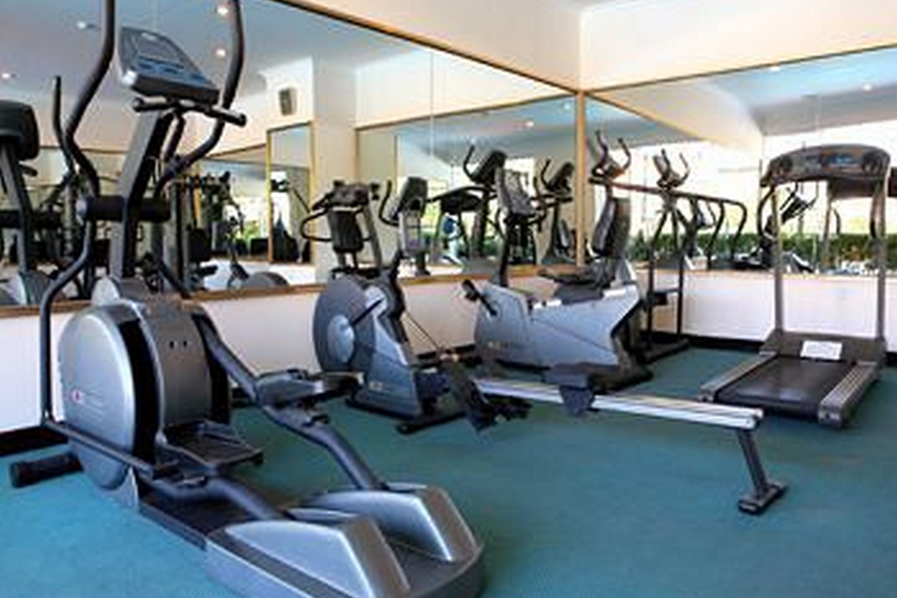 A gym with various exercise equipment including treadmills, elliptical machines, and stationary bikes.