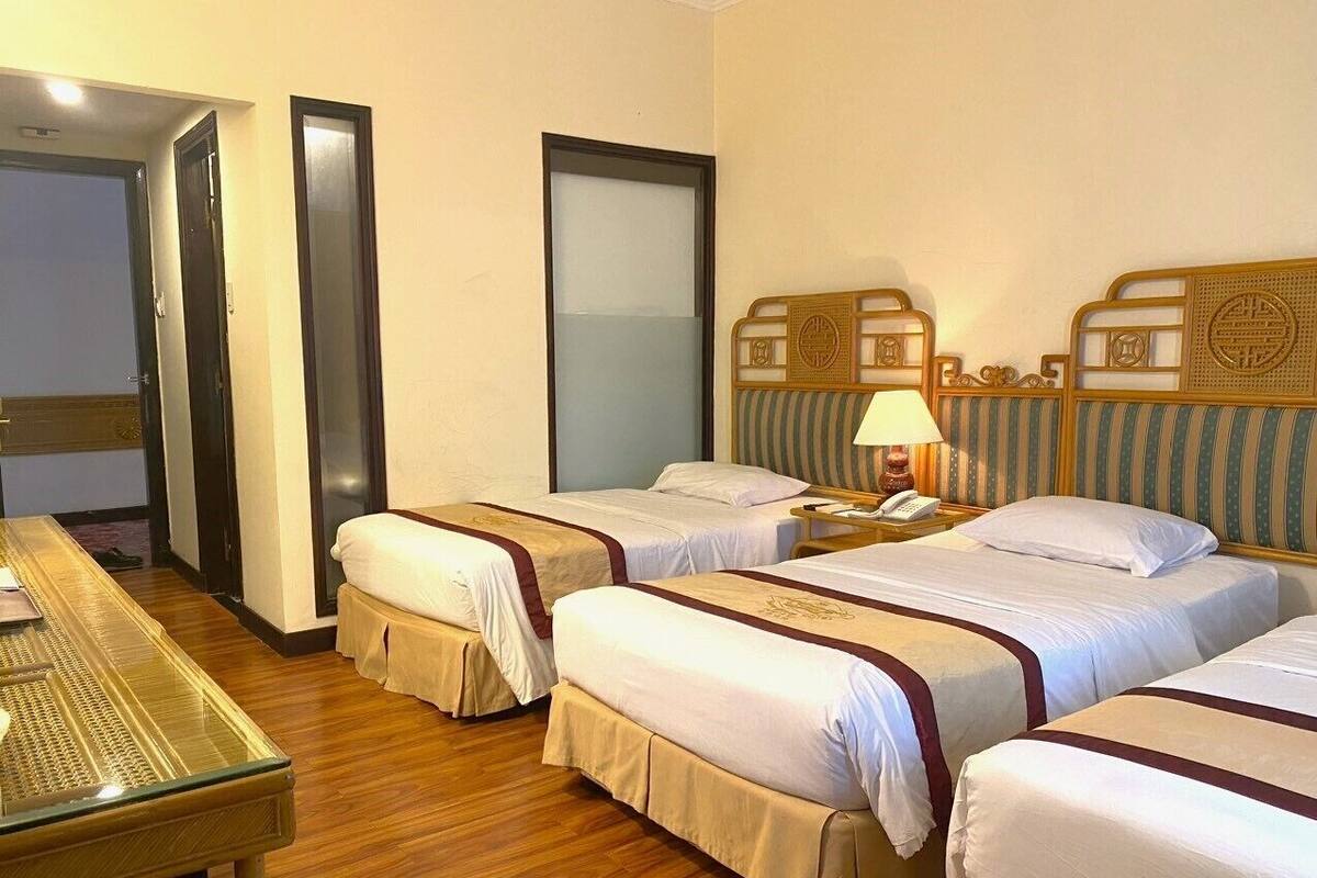 Een hotelkamer met vier enkele bedden, een houten tafel en een stoel.