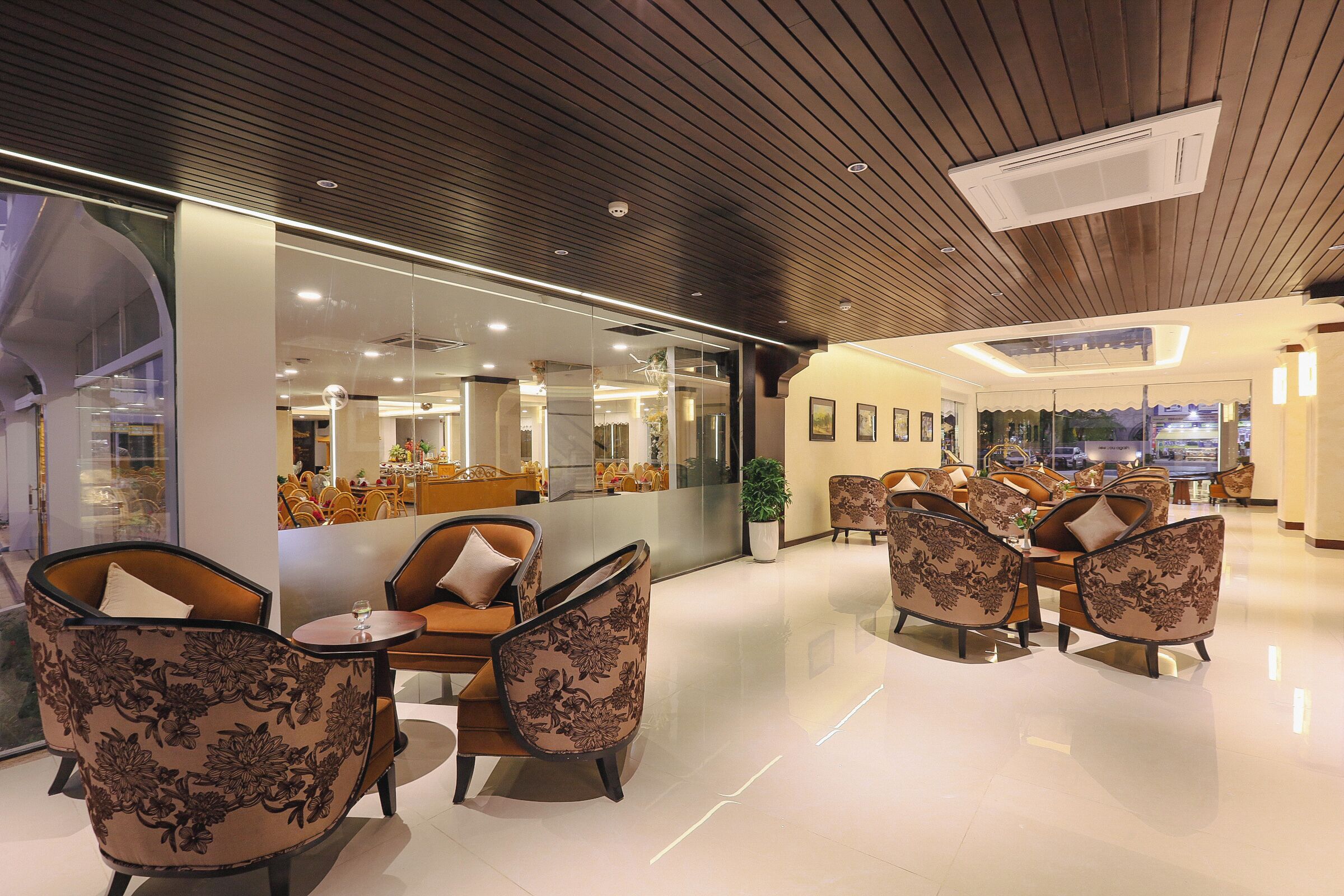 A modern lobby with a glass partition, comfortable seating, and a clean, polished floor.