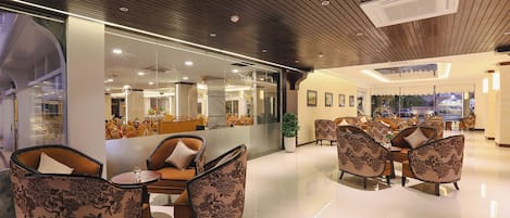A modern lobby with a glass partition, comfortable seating, and a clean, polished floor.