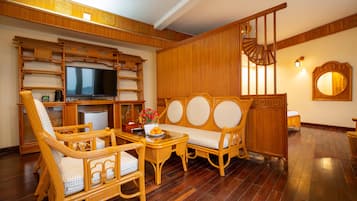 A traditional room with a television, wicker furniture, a wooden staircase, and a mirror.