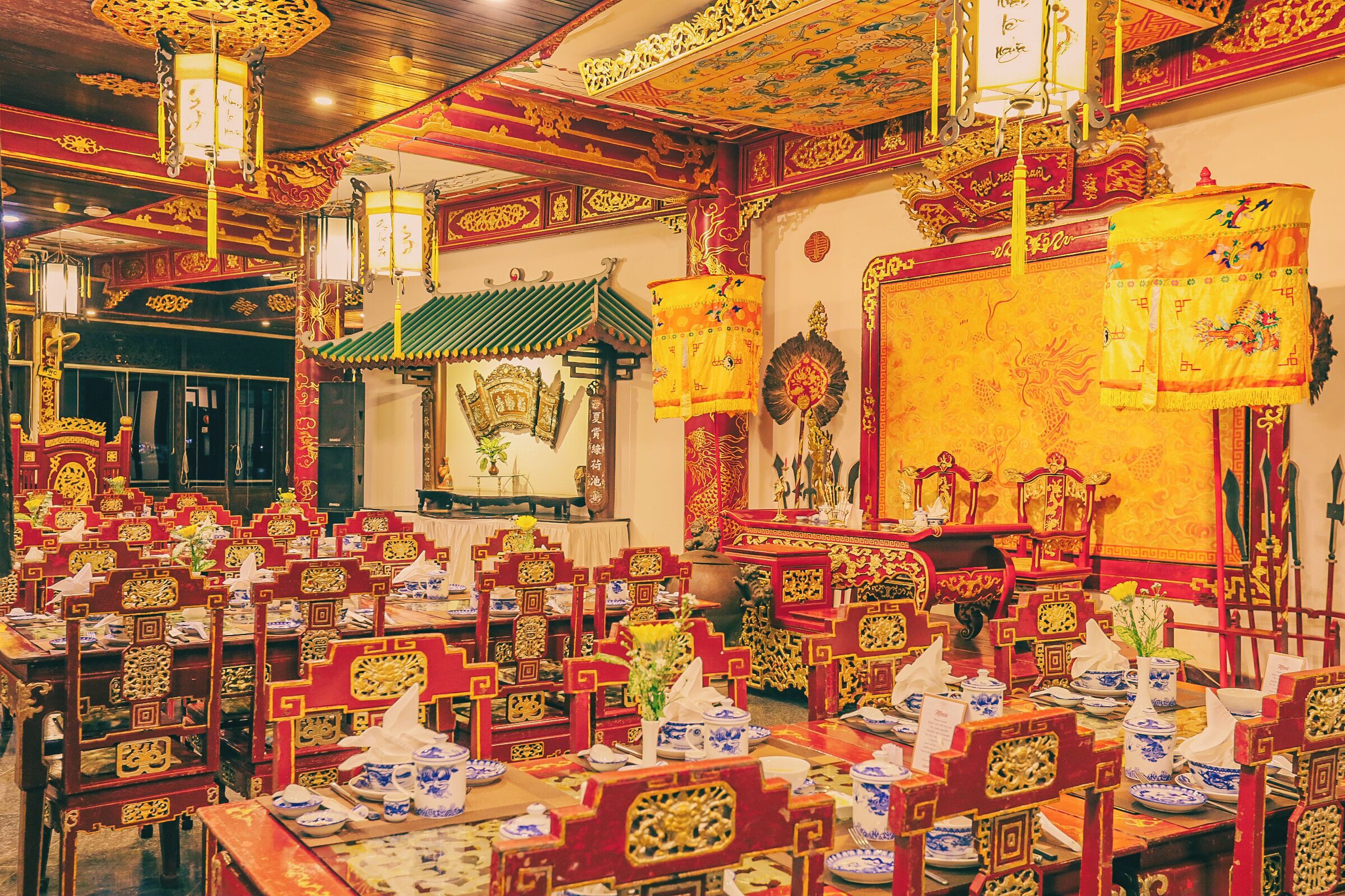 Een traditionele Chinese feestzaal met gedetailleerde rode en gouden decoraties, houten meubels en een centraal altaar.
