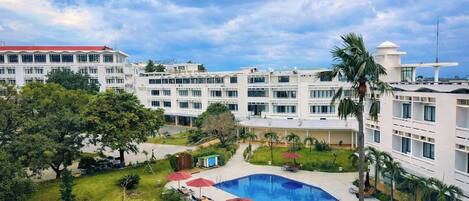 A hotel with multiple floors, a swimming pool, and a well-maintained garden.