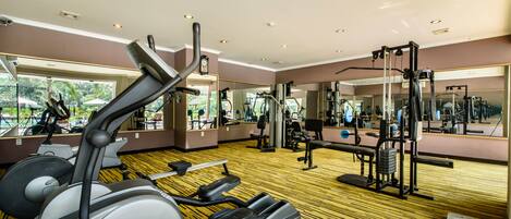 Un gimnasio con equipo cardiovascular, máquinas de pesas y espejos.