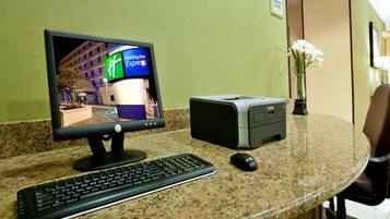 A hotel reception desk with a computer, keyboard, mouse, and printer.