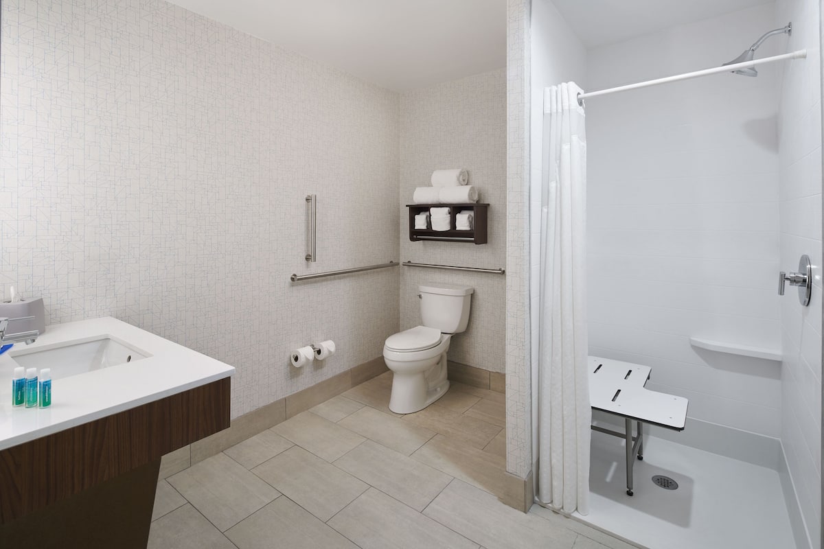 A modern bathroom with a white sink, toilet, and shower area.