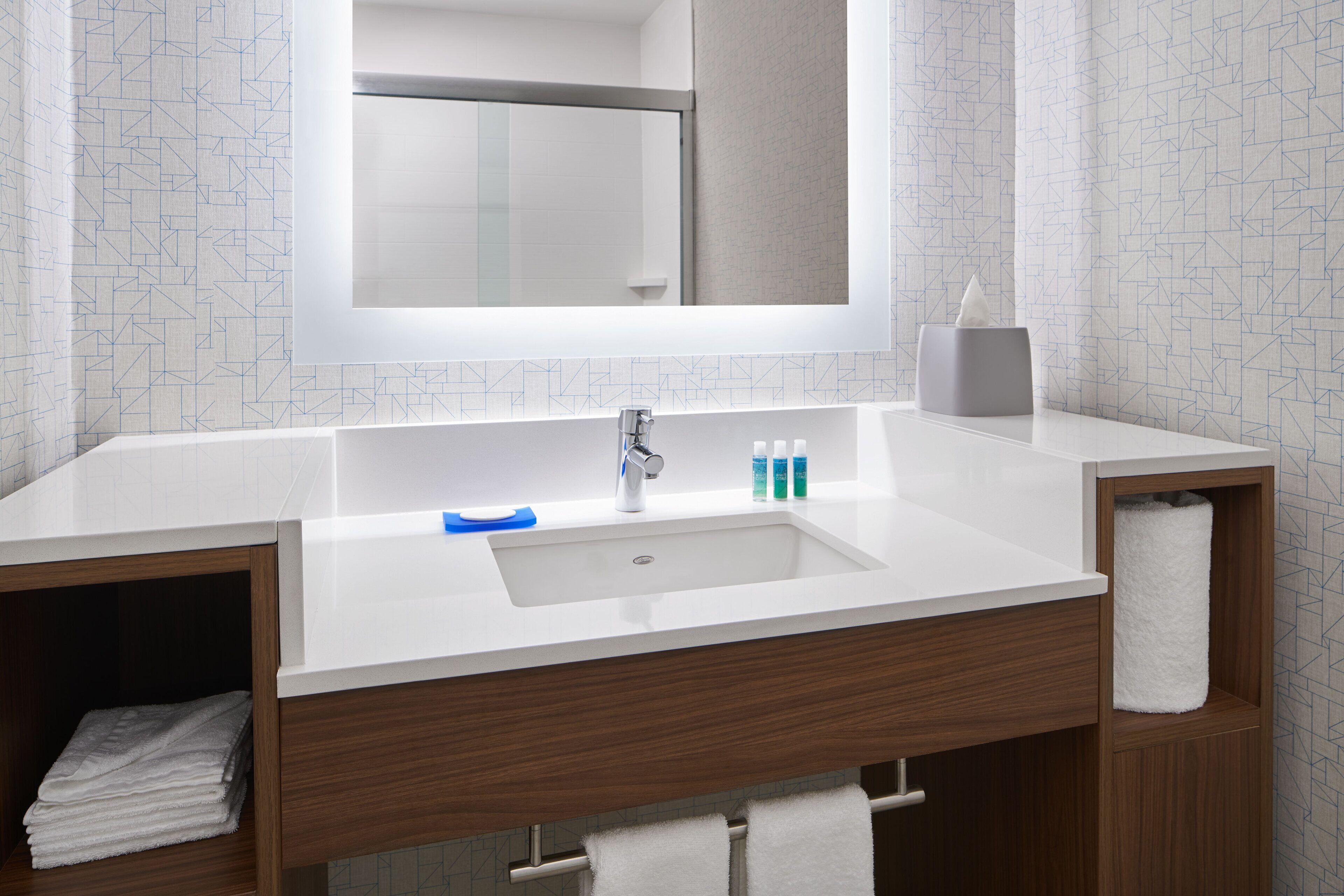 A bathroom with a white sink, a mirror above it, and a towel rack.