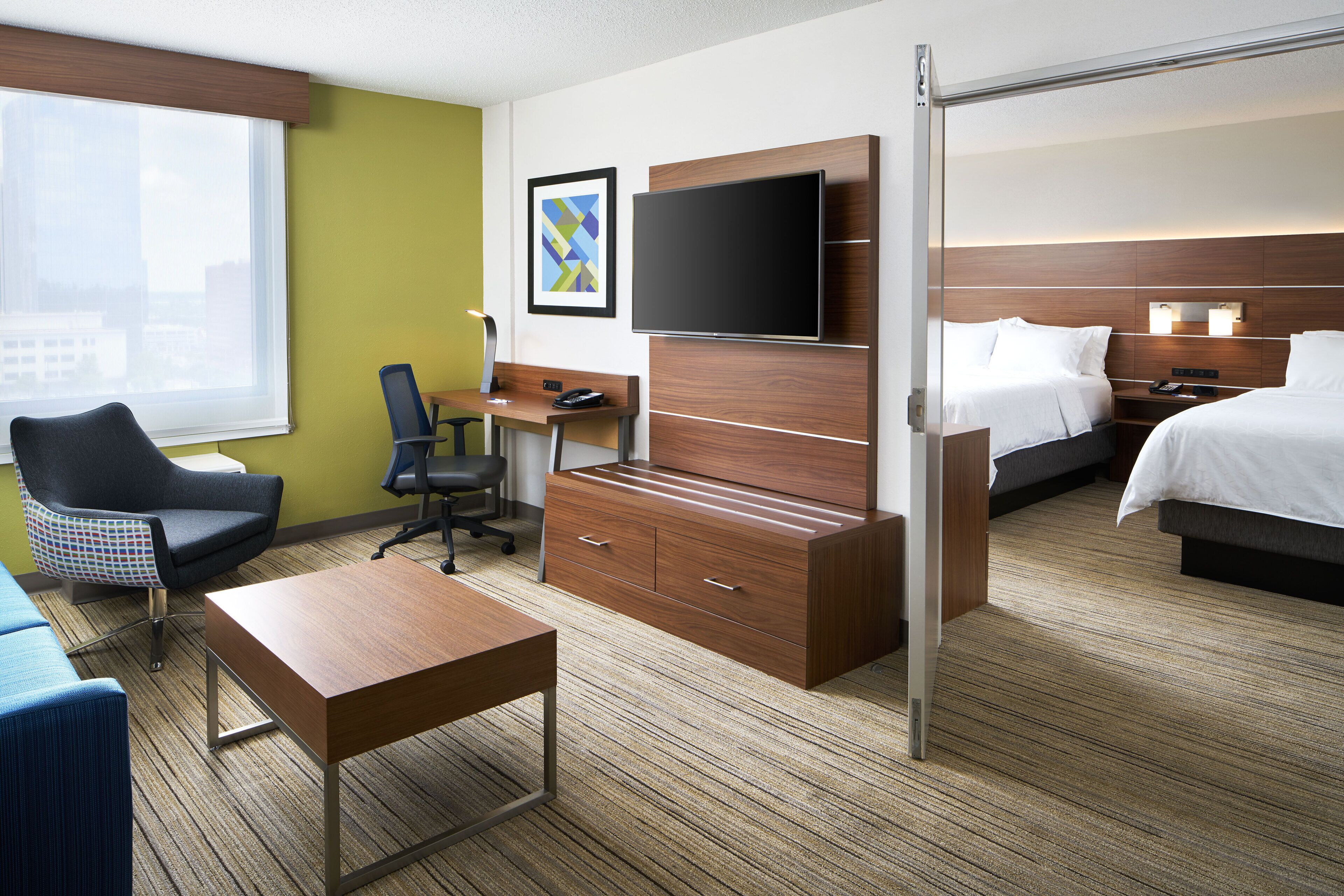Una habitación de hotel con escritorio, silla, cama y televisor.