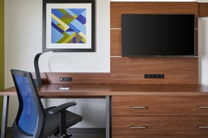 A modern hotel room with a wooden desk, a black office chair, a flat-screen TV mounted on a wooden cabinet, and a framed abstract art piece on the wall. - Holiday Inn Express Richmond Downtown by IHG (Richmond)