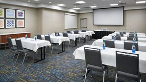 A conference room with multiple tables, chairs, and a projector screen. - Holiday Inn Express Richmond Downtown by IHG (Richmond)