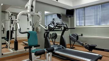Un gimnasio con equipo de ejercicio, una cinta de correr y un espejo.