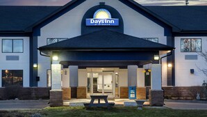 Edificio de Days Inn by Wyndham con entrada cubierta, asientos exteriores y cielo despejado.