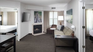 A hotel room with a bed, a sofa, a desk, a fireplace, and a TV. - Residence Inn by Marriott Boston Westford (Westford)