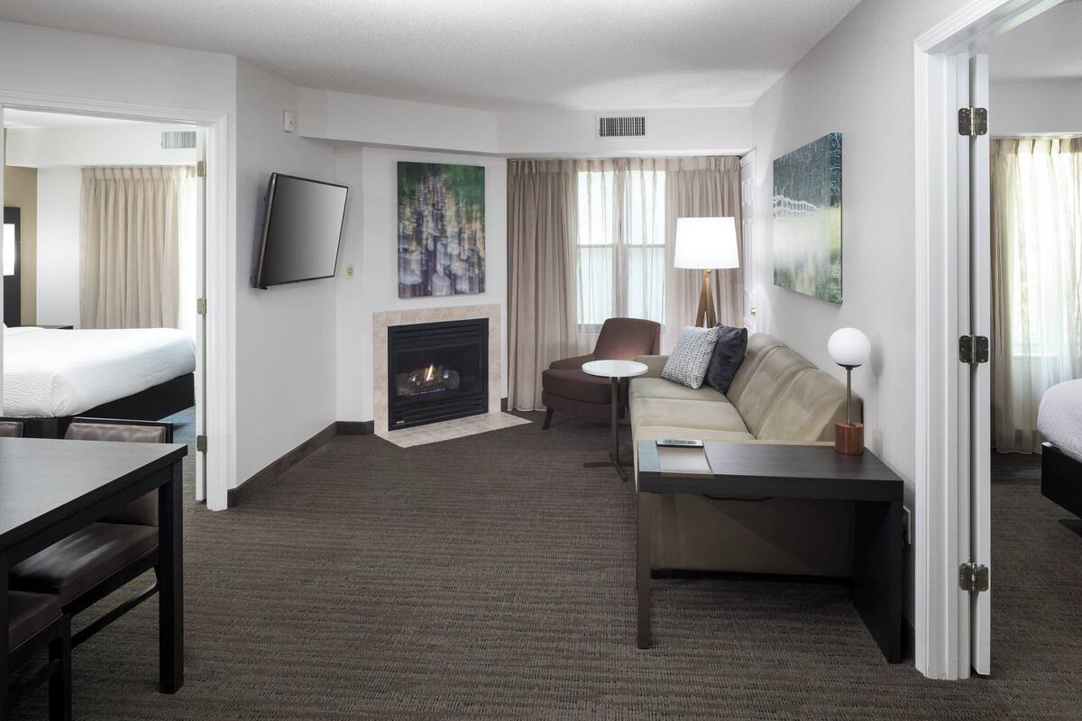 Habitación de hotel con cama, sofá, escritorio, chimenea y televisor.