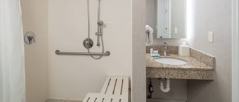 Baño con ducha, barra de apoyo y lavamanos.