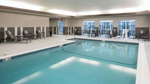 An indoor swimming pool with multiple lounge chairs and a lifeguard stand. - Residence Inn by Marriott Boston Westford (Westford)