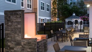 An outdoor patio area with stone walls, tables, and chairs. - Residence Inn by Marriott Boston Westford (Westford)