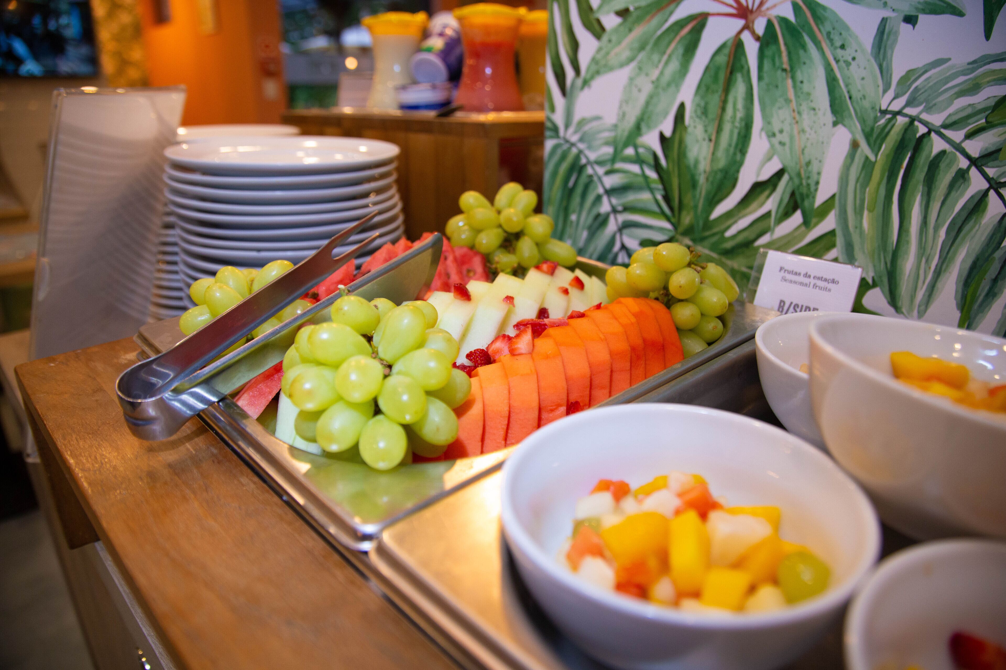 A buffet table with various fruits and a sign indicating seasonal fruits.