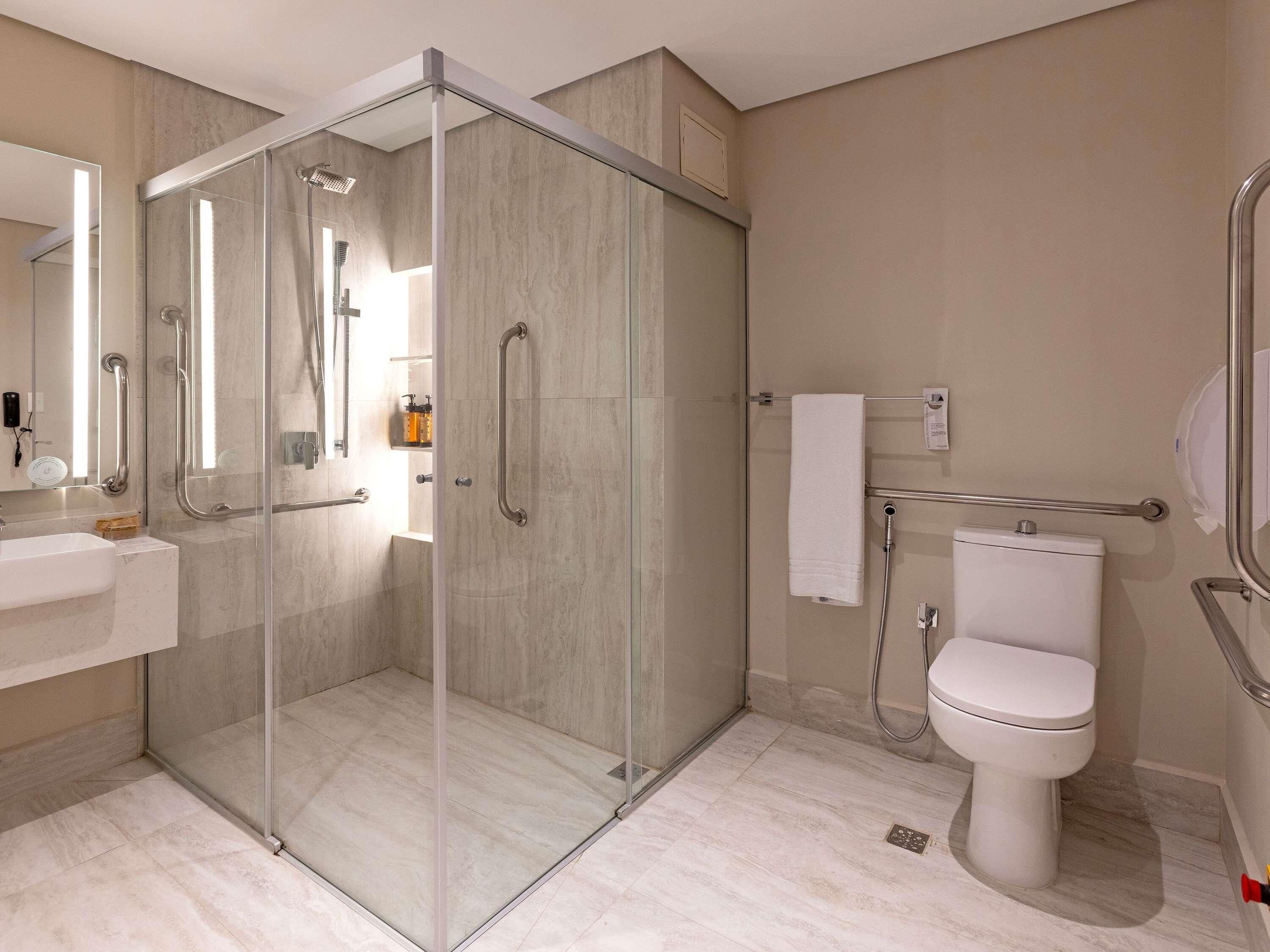 Une salle de bain moderne dotée d’une douche à parois de verre, de toilettes, d’un lavabo et d’un porte-serviettes.