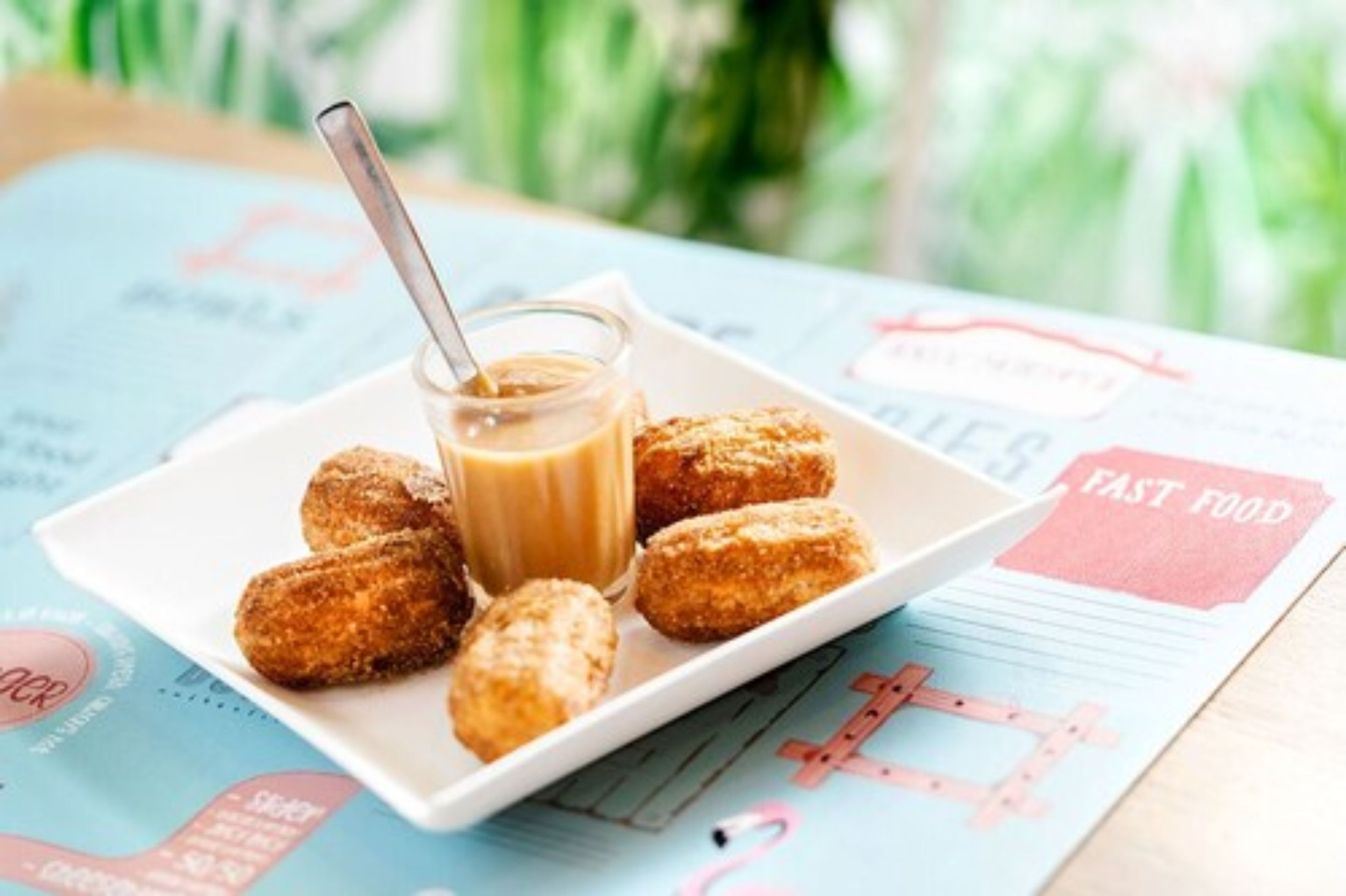 Um prato de bolinhos fritos com molho para acompanhar e uma colher, num menu com um símbolo de 'X'.