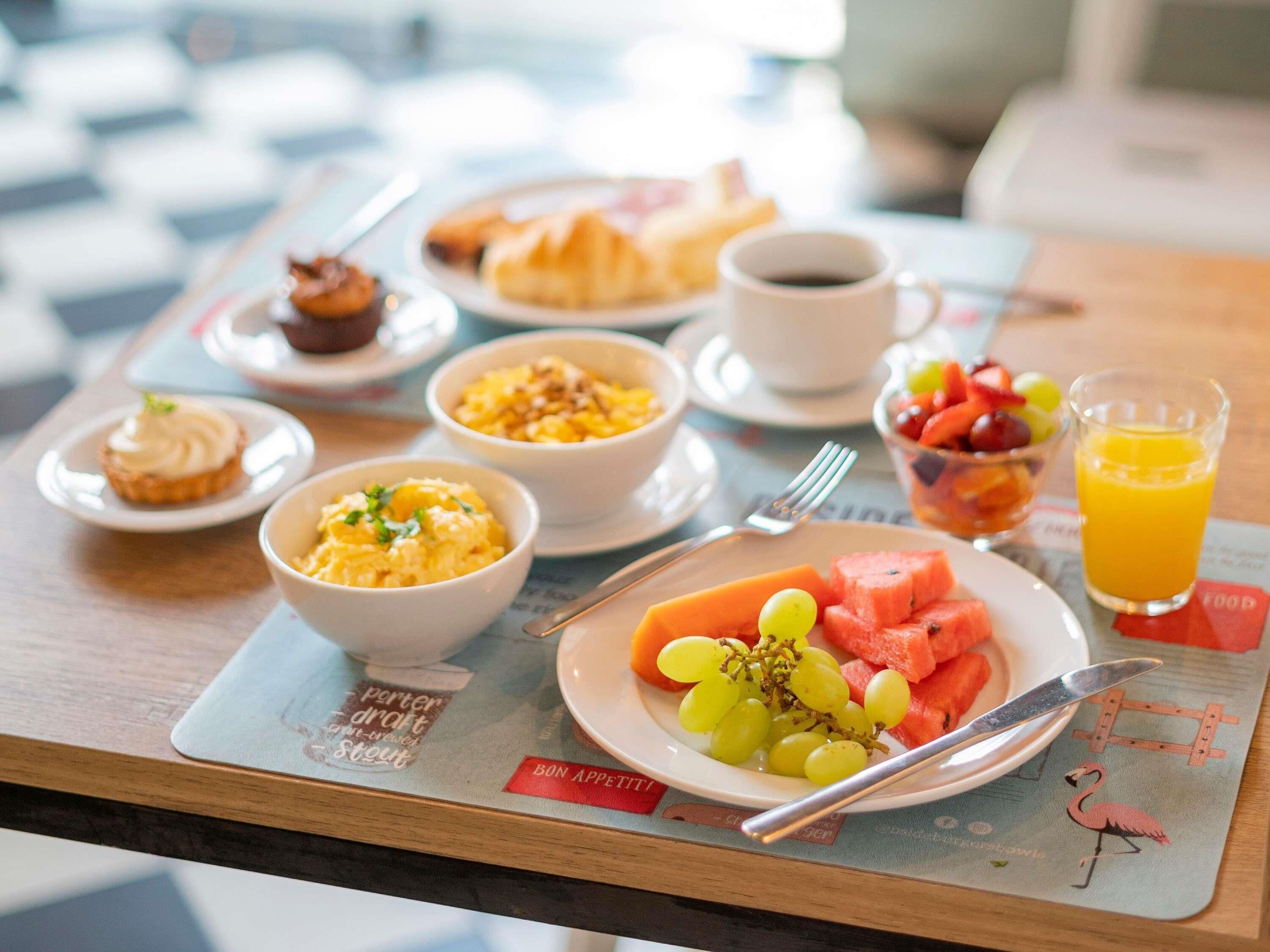 A breakfast tray with various foods and a glass of orange juice.