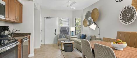 A modern kitchen with a dining area, featuring a wooden table, chairs, and a ceiling fan.