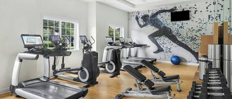 A gym with treadmills, elliptical machines, and weightlifting equipment.