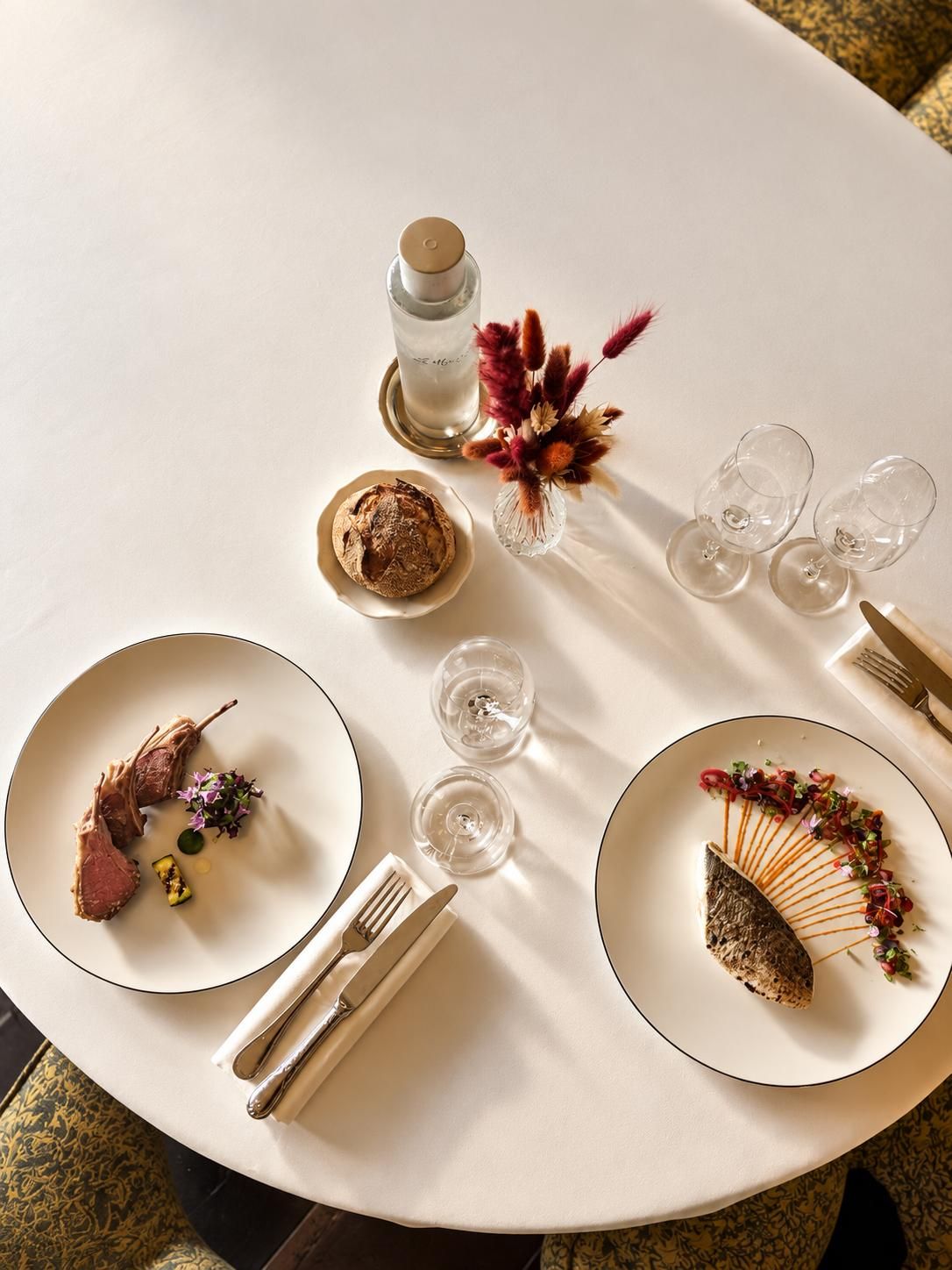 A round dining table with plates, cutlery, and a candle.