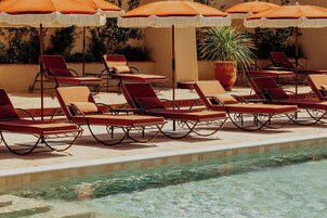 A poolside area with lounge chairs and orange umbrellas.