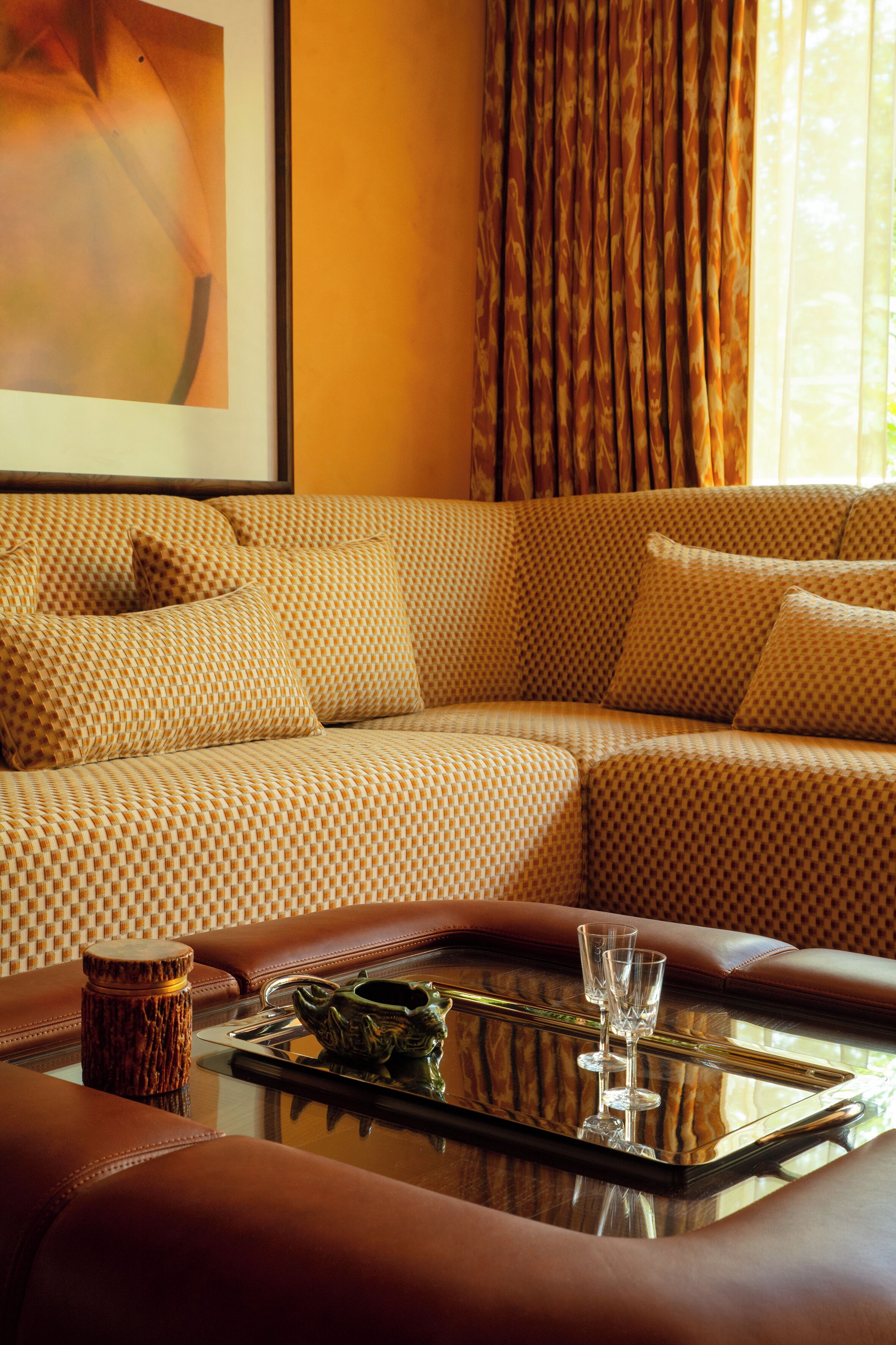 A modern living room with a patterned sofa, a glass coffee table with a tray, and a decorative item.
