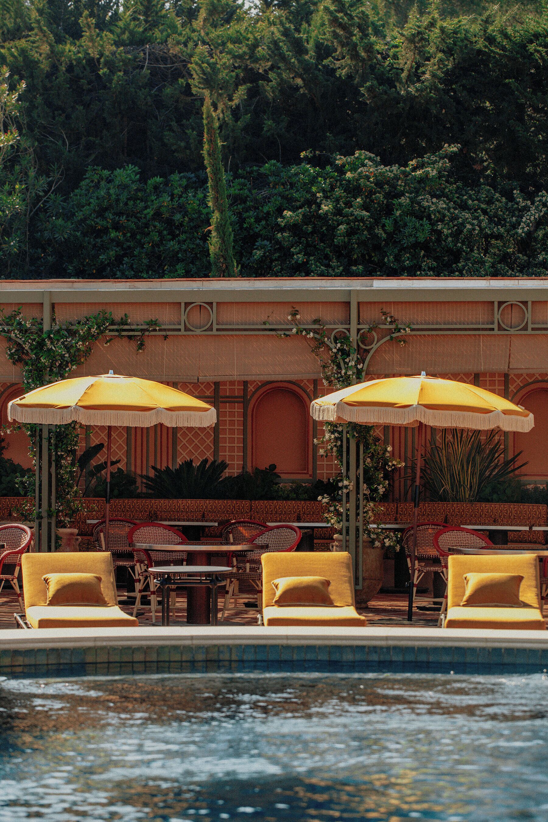A poolside area with yellow umbrellas, red chairs, and a tiled pool.